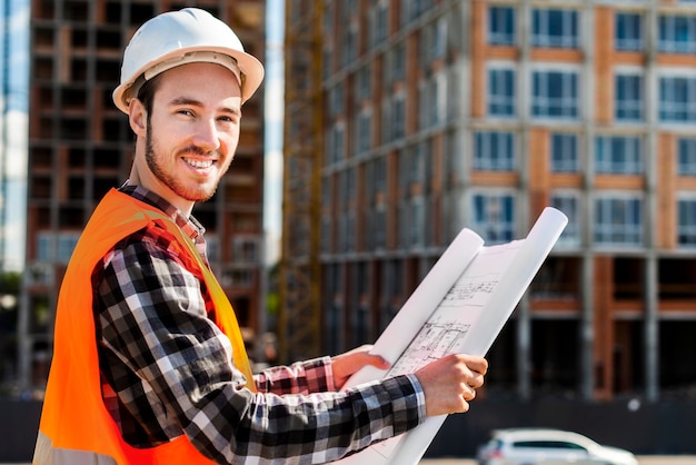 Tiro médio, vista lateral, de, engenheiro construção, olhando câmera