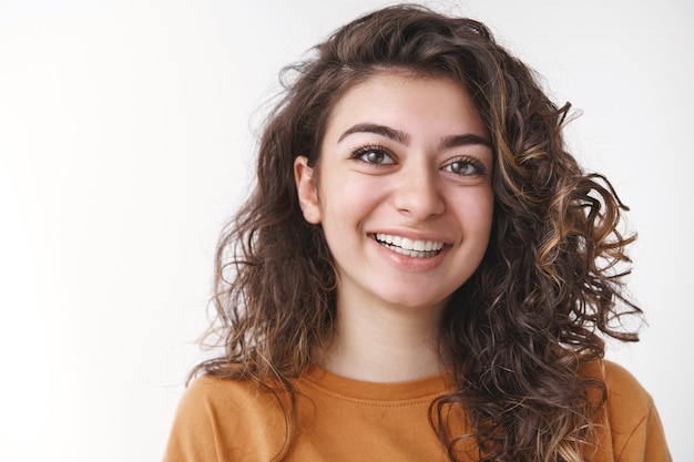 Tiro na cabeça despreocupado feliz sortudo jovem de cabelos cacheados positivo caucasiano mulher rindo, sorrindo, se divertindo, aproveitando o dia perfeito, conversando simpáticos colegas de trabalho falando, em pé fundo branco