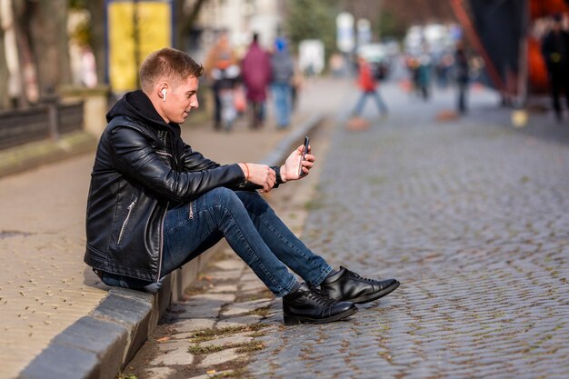 Tiro no escuro jovem ouvindo música no fone de ouvido fora