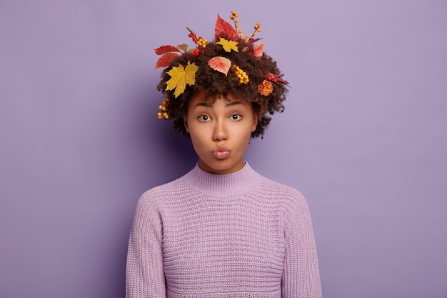 Foto grátis tiro sincero de mulher de cabelo encaracolado triste faz careta ofensiva, mantém os lábios arredondados, tem caminhada de outono, não gosta de tempo chuvoso, usa suéter de malha casual, fica dentro de casa.