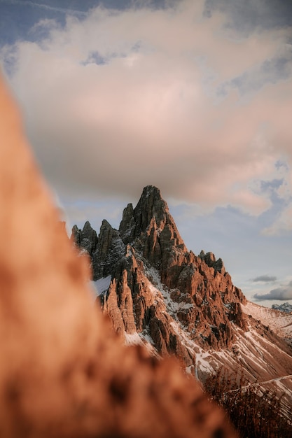 Tiro vertical das Dolomitas sob um céu nublado e luz solar na Itália