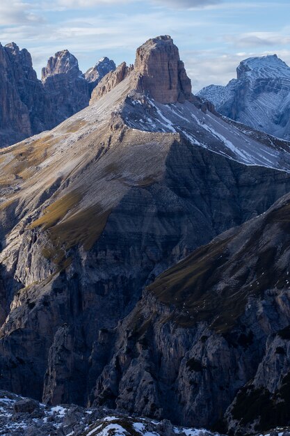 Tiro vertical das rochas cobertas de neve nos Alpes italianos