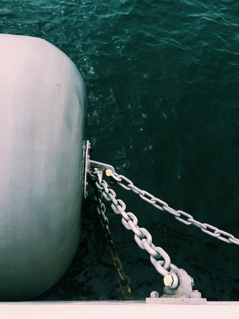 Foto grátis tiro vertical de correntes de metal conectadas a um barril em um lado do barco