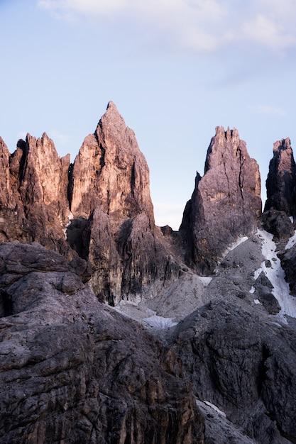 Foto grátis tiro vertical de grandes rochas no topo de uma montanha com um céu claro no