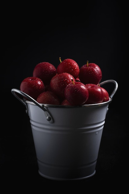 Tiro vertical de maçãs vermelhas frescas em um balde isolado em um fundo preto