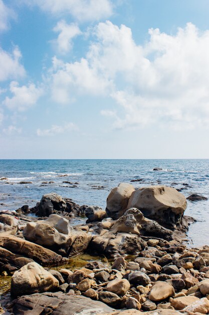 Tiro vertical de pedras à beira-mar sob o céu nublado