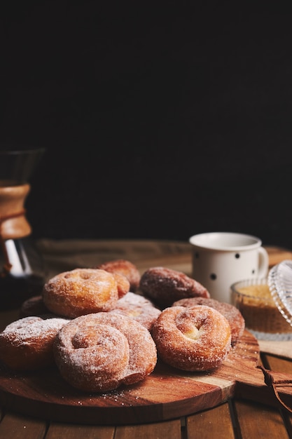 Tiro vertical de rosquinhas de cobra com açúcar de confeiteiro e café químico em uma mesa de madeira