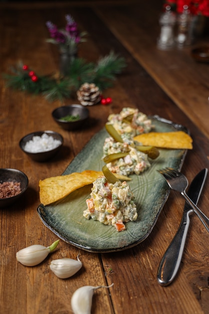 Tiro vertical de salada olivier servida com batatas fritas ao lado dos ingredientes