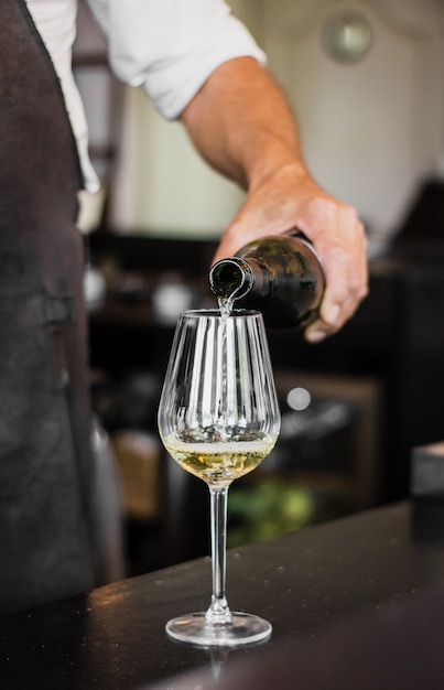 Tiro vertical de um barman, derramando um vinho em um copo