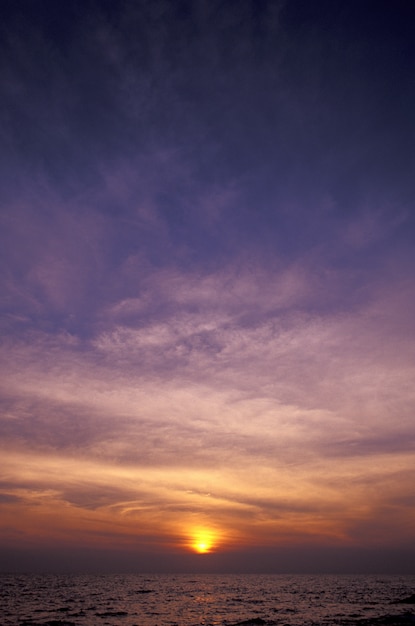 Tiro vertical de um céu roxo e amarelo acima do mar ao pôr do sol