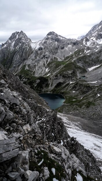 Tiro vertical de um lago cercado por montanhas sob um céu nublado