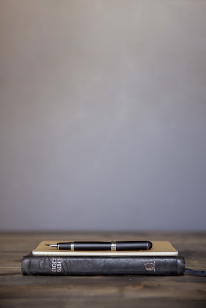 Foto grátis tiro vertical de um notebook com a caneta-tinteiro no topo sobre uma superfície de madeira