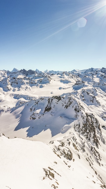 Tiro vertical de um pico de montanha cênico coberto de neve durante o dia.
