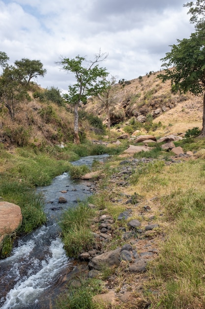 Tiro vertical de um rio cercado por rochas e seixos capturados no quênia, nairobi, samburu