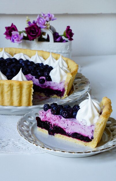 Tiro vertical de uma deliciosa torta com creme e mirtilos em um prato na mesa