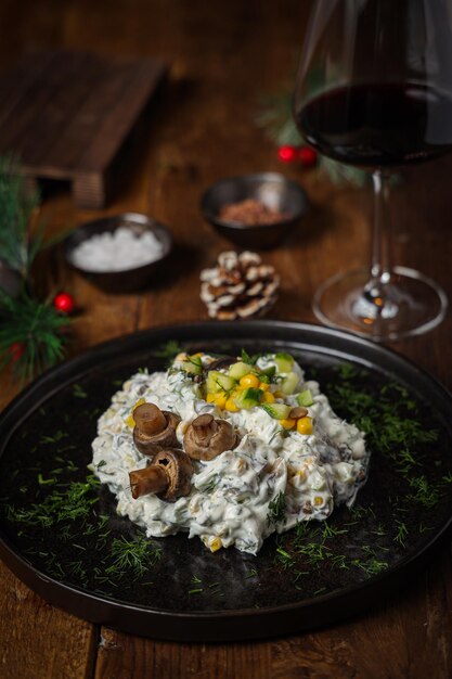 Tiro vertical de uma mesa de jantar de madeira com salada de legumes e vinho de especiarias durante as férias