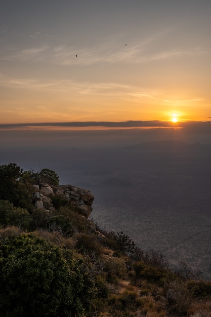 Tiro vertical de uma montanha coberta de árvores e o pôr do sol capturado no Quênia, Nairobi, Samburu