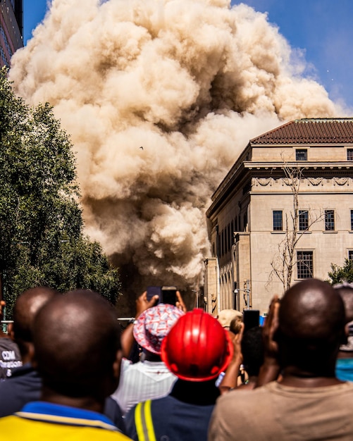 Tiro vertical de uma multidão de pessoas assistindo e filmando a fumaça de uma explosão