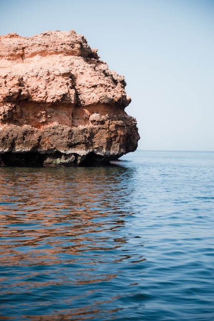 Foto grátis tiro vertical de uma pedra enorme no meio do mar calmo
