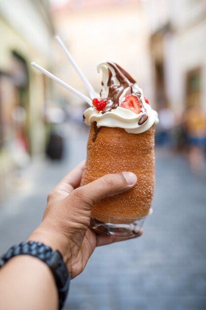 Tiro vertical de uma pessoa segurando um sorvete cronut em Praga, República Tcheca
