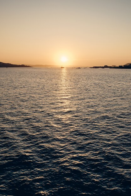 Tiro vertical do mar, refletindo a luz do sol com um lindo céu