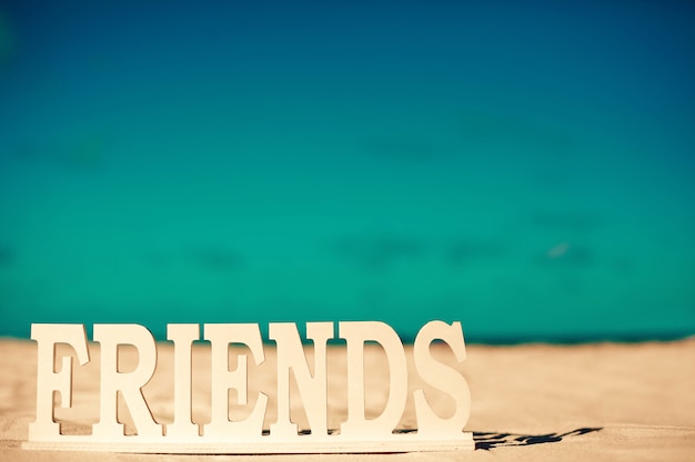 Título de amigos na areia branca atrás do céu azul perto do oceano