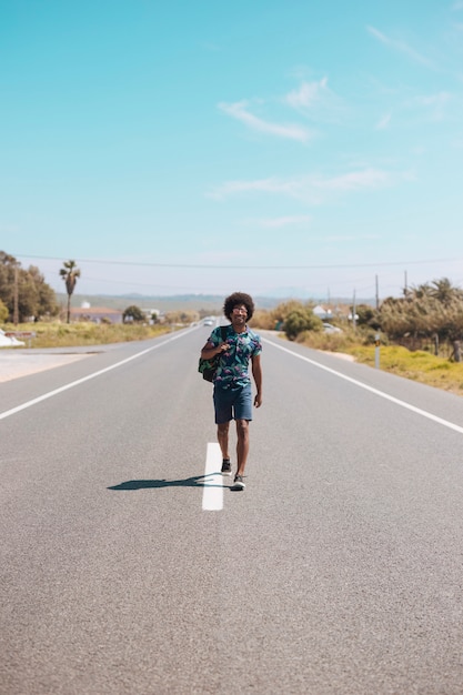 Étnico homem andando na estrada vazia