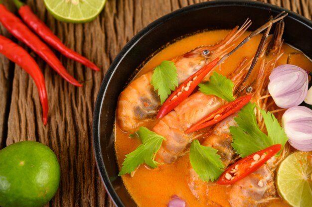 Tom Yum Kung Thai sopa de camarão picante com capim-limão, limão, galanga e pimenta na mesa de madeira, Tailândia