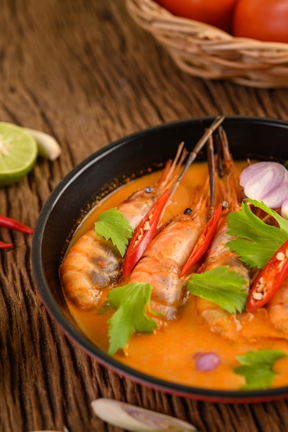 Tom yum kung thai sopa de camarão picante com capim-limão, limão, galanga e pimenta na mesa de madeira, tailândia