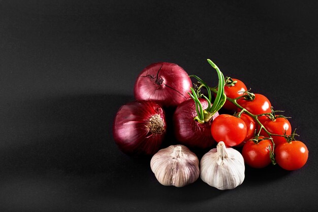 Tomate, cebola e alho são isolados em um fundo preto