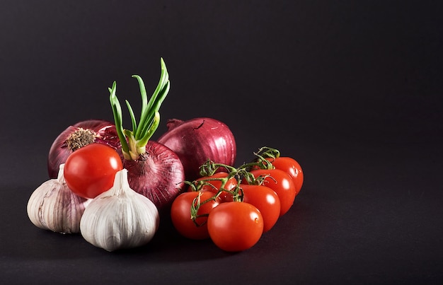 Tomate, cebola e alho são isolados em um fundo preto