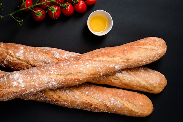 Foto grátis tomate cereja, óleo e pão longo com farinha.