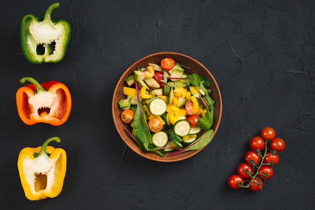 Tomate cereja; pimentão cortado à metade e salada vegan fresca no pano de fundo concreto