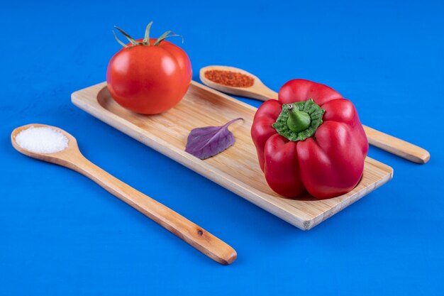 Tomate fresco e pimentão vermelho em uma placa de madeira com especiarias
