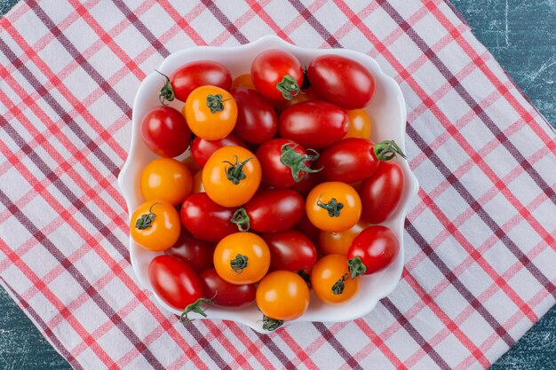 Tomates cereja amarelos e vermelhos isolados na superfície azul.