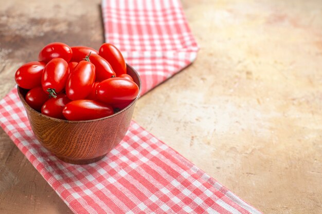 Tomates cereja de vista frontal em uma tigela de madeira um pano de prato em um espaço livre âmbar