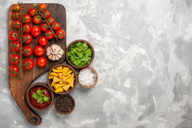 Tomates cereja frescos de vista superior com diferentes temperos e verduras na superfície branca