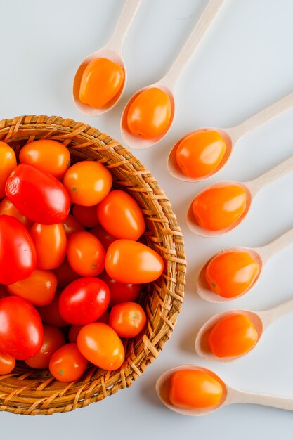 Tomates coloridos em colheres de madeira e vista superior do cesto