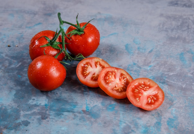 Tomates de alto ângulo vista com fatias na superfície texturizada. horizontal