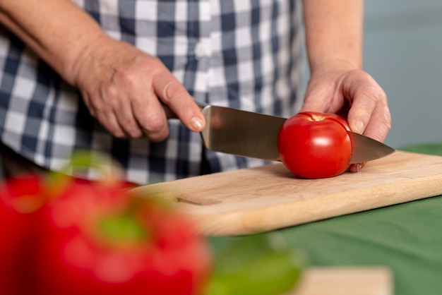 Tomates de corte de mulher mais velha em close-up