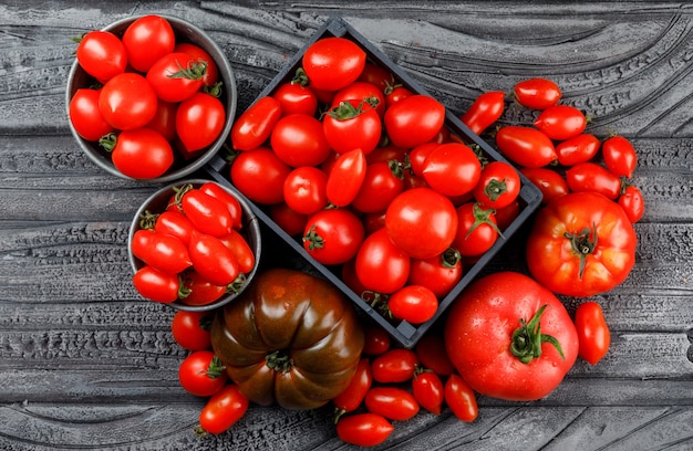 Tomates diferentes em caixa de madeira, mini baldes em uma parede de madeira cinza. vista do topo.