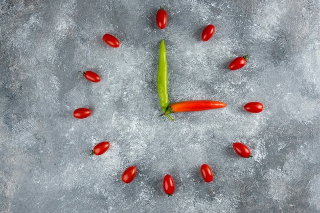 Tomates e pimentões formaram-se como um relógio na superfície do mármore.