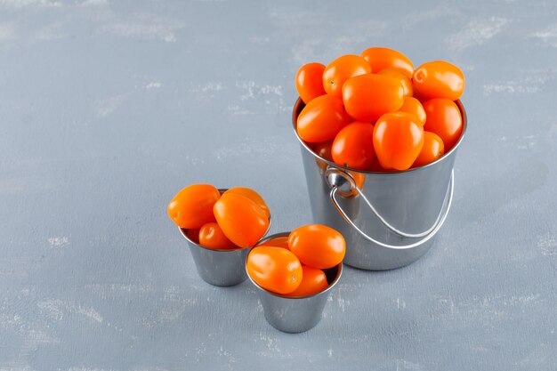 Tomates em baldes em uma mesa de gesso. vista de alto ângulo.