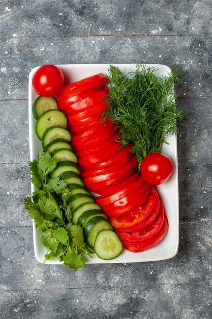 Tomates frescos fatiados de vista superior salada elegantemente projetada no espaço cinza