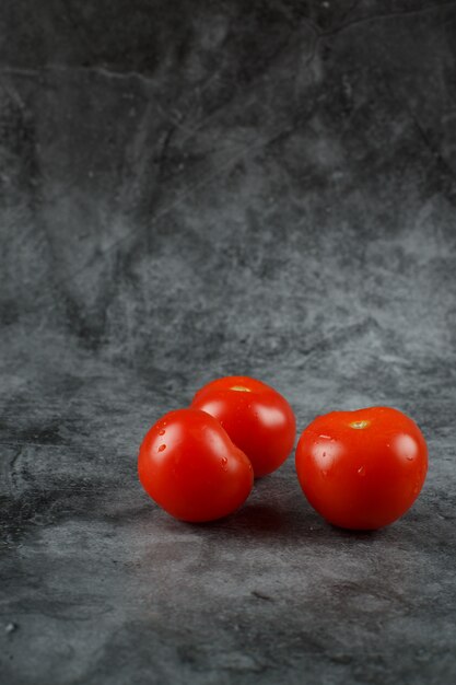 Tomates frescos vermelhos sobre um fundo de pedra.