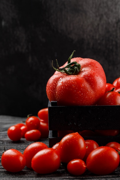 Foto grátis tomates frios em uma caixa de madeira na parede cinza e escura, vista lateral.
