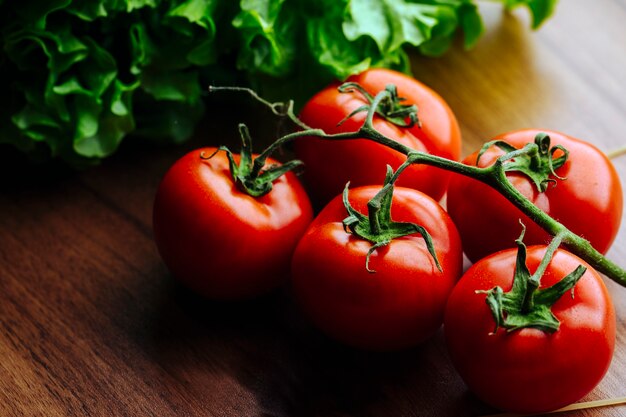 Tomates inteiros na superfície de madeira