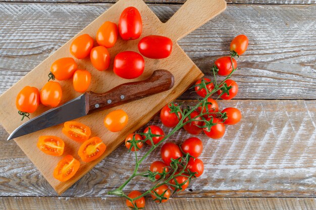 Tomates maduros com faca plana leigos na tábua de madeira e