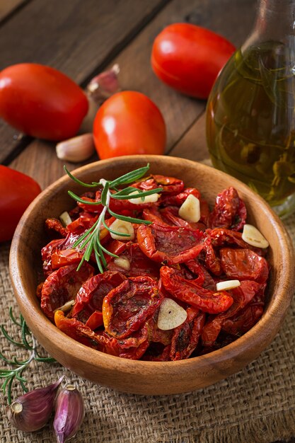 Tomates secos ao sol com ervas e alho em uma tigela de madeira