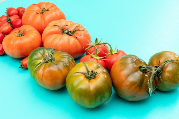 Foto grátis tomates verdes de laranja e cereja no azul